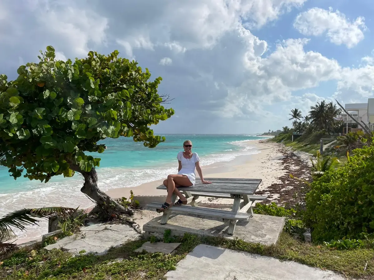 A guest on a weathered picnic bench above a turquoise beach