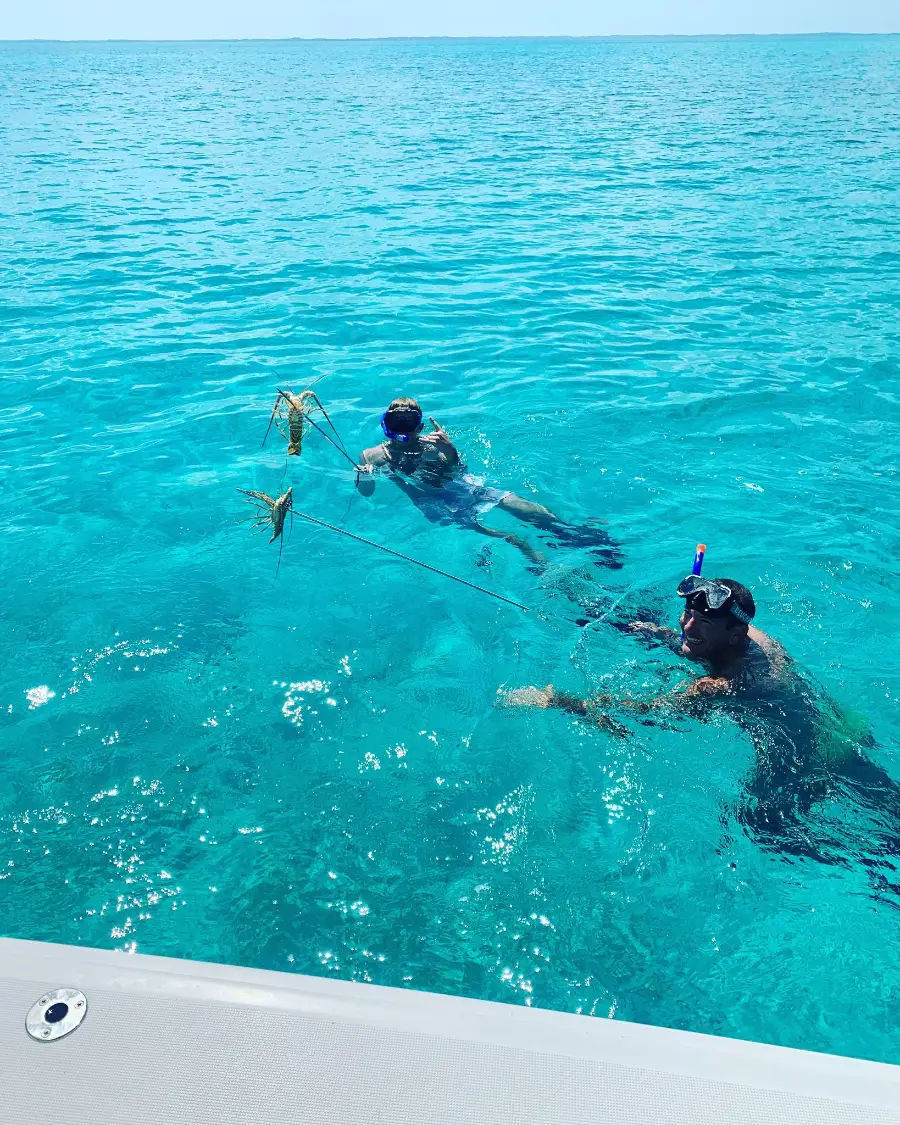 Guests surfacing with crawfish speared on the reef in the Sea of Abaco