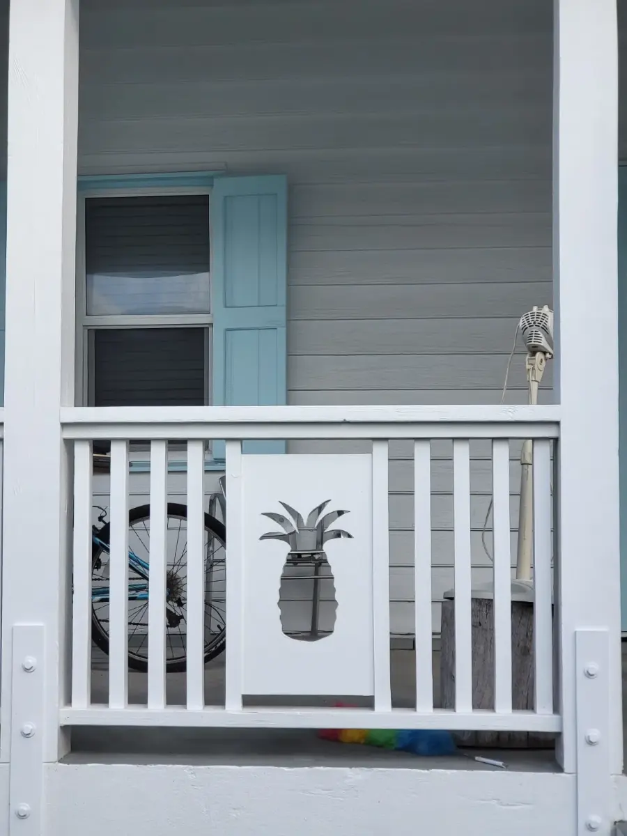 A pineapple cut-out on a white porch railing
