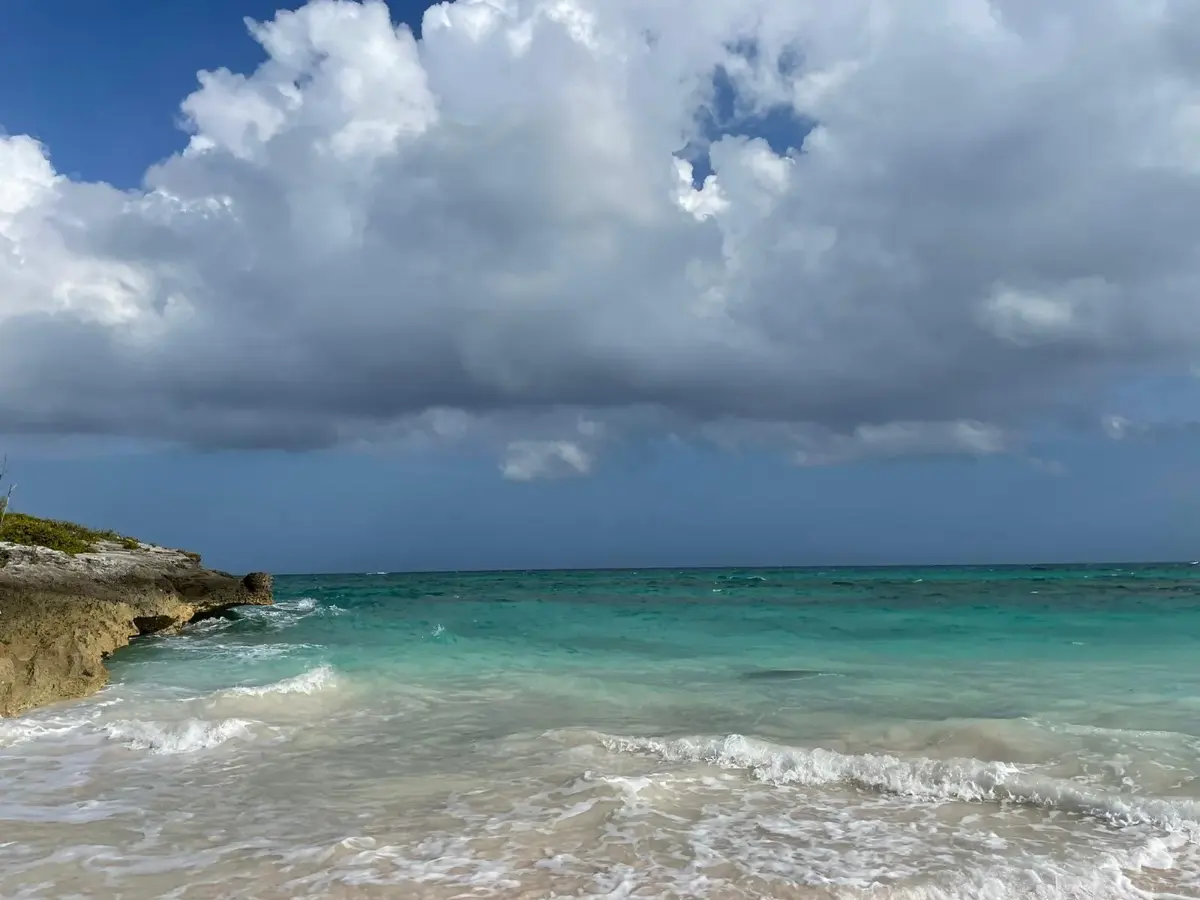 Waves breaking into a rocky cove under towering clouds
