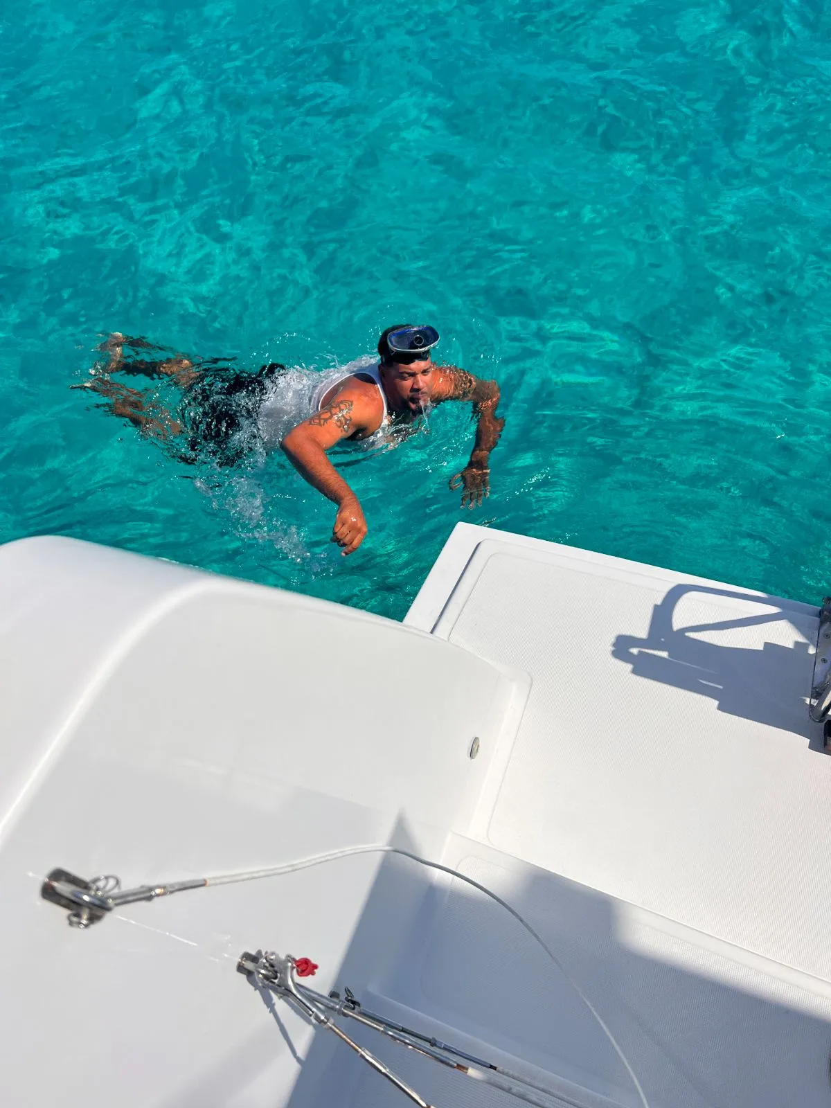 A snorkeller swimming back to the catamaran in clear turquoise water