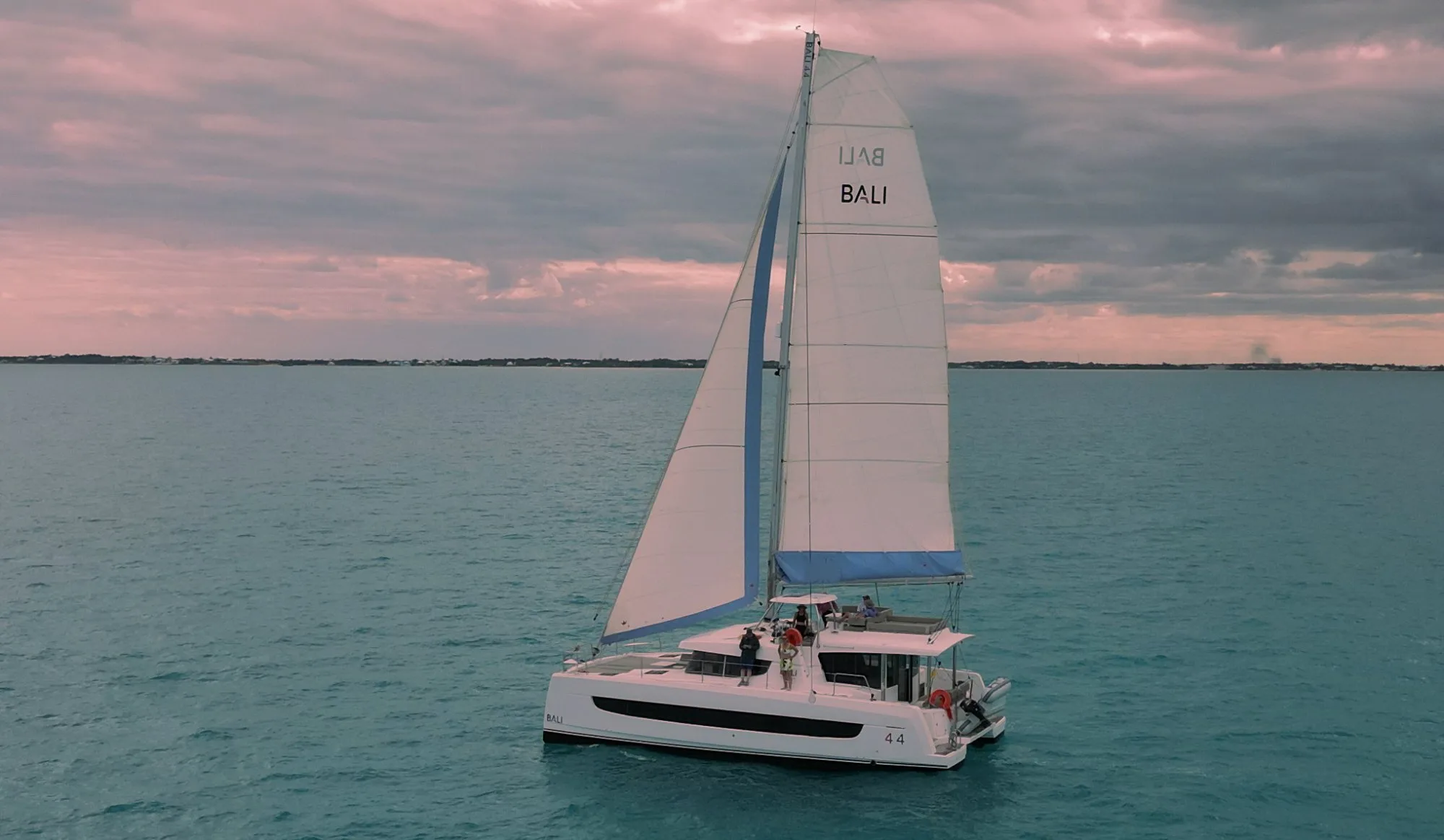 Ptarmigan, a Bali 4.4 catamaran, under sail at sunset in the Sea of Abaco